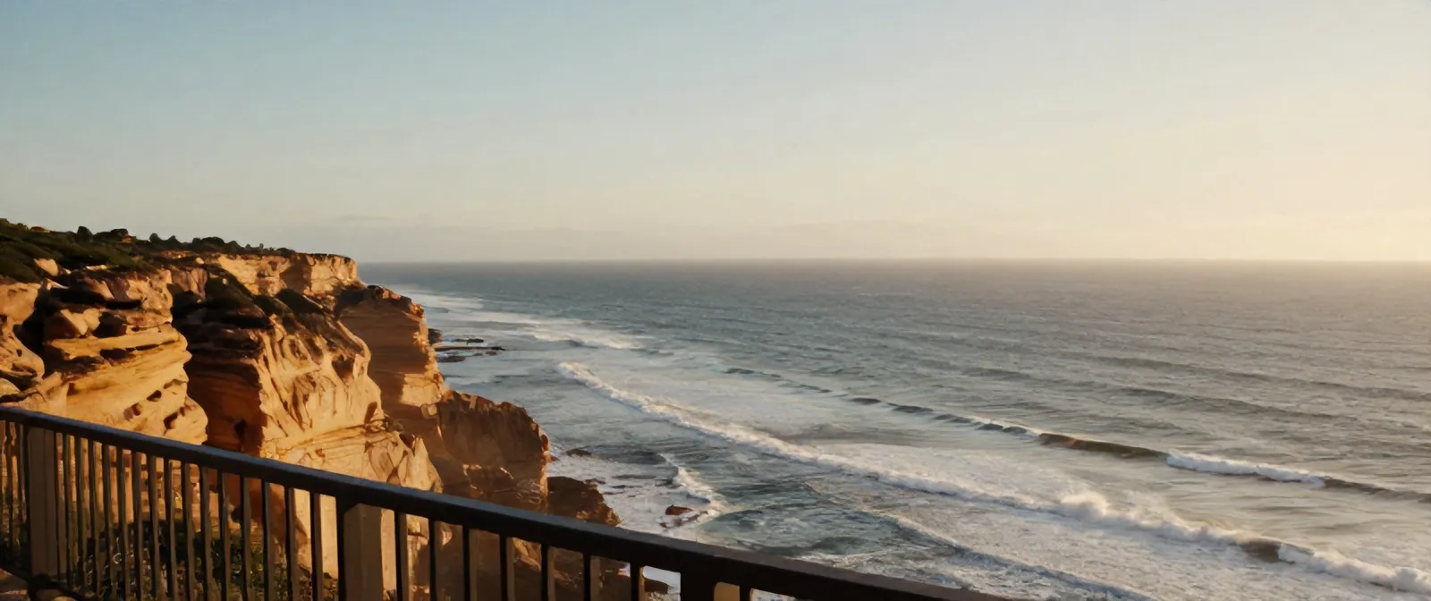 The Atlantic seen from the terrace railing of Casa Mirante, ochre cliffs dropping to long lines of swell