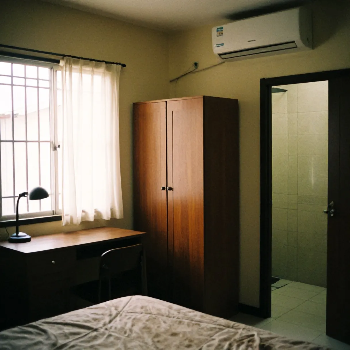Kamar Wisma Melati dengan meja belajar, lemari, AC, dan pintu kamar mandi dalam