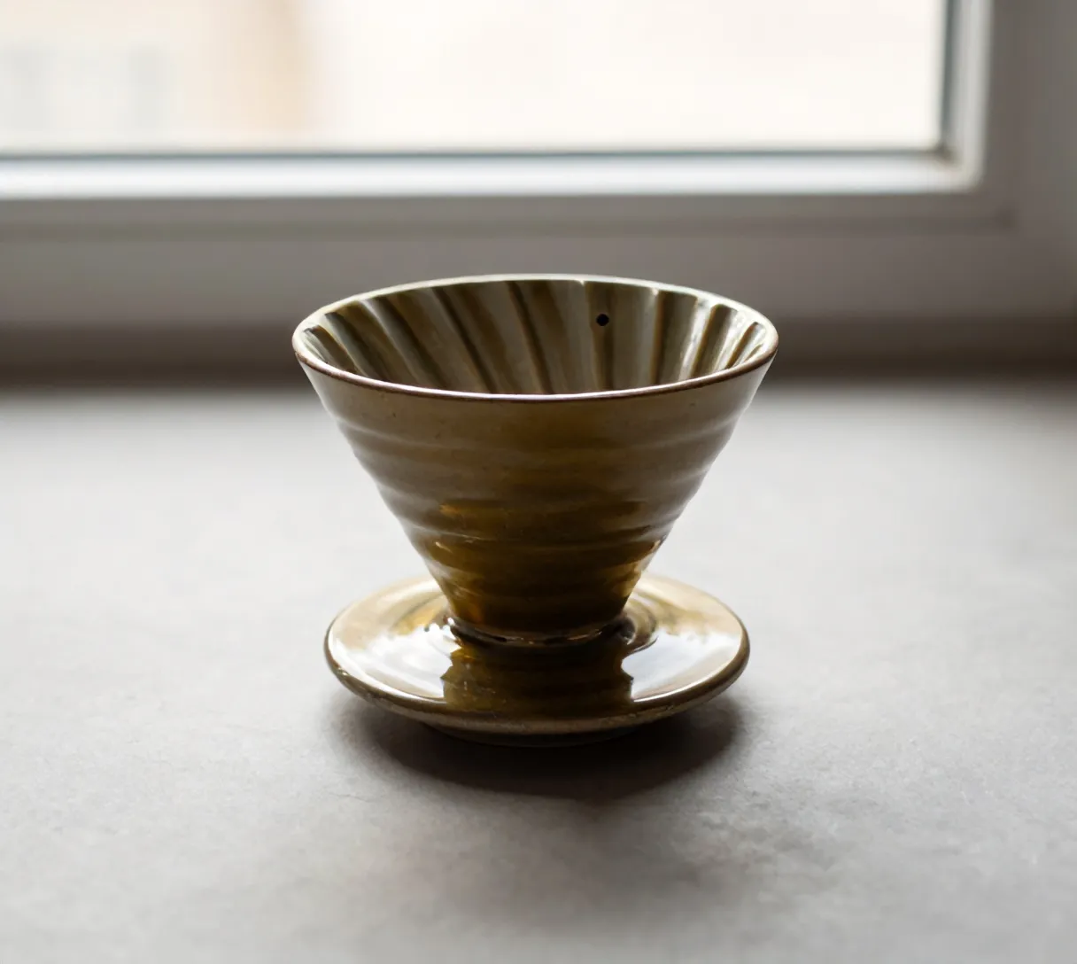 The Kiln dripper in ochre-brass glaze, alone on paper grey