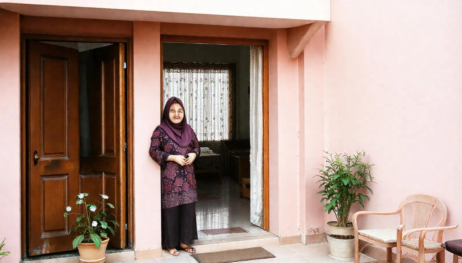 Bu Ratna berdiri di pintu depan Wisma Melati