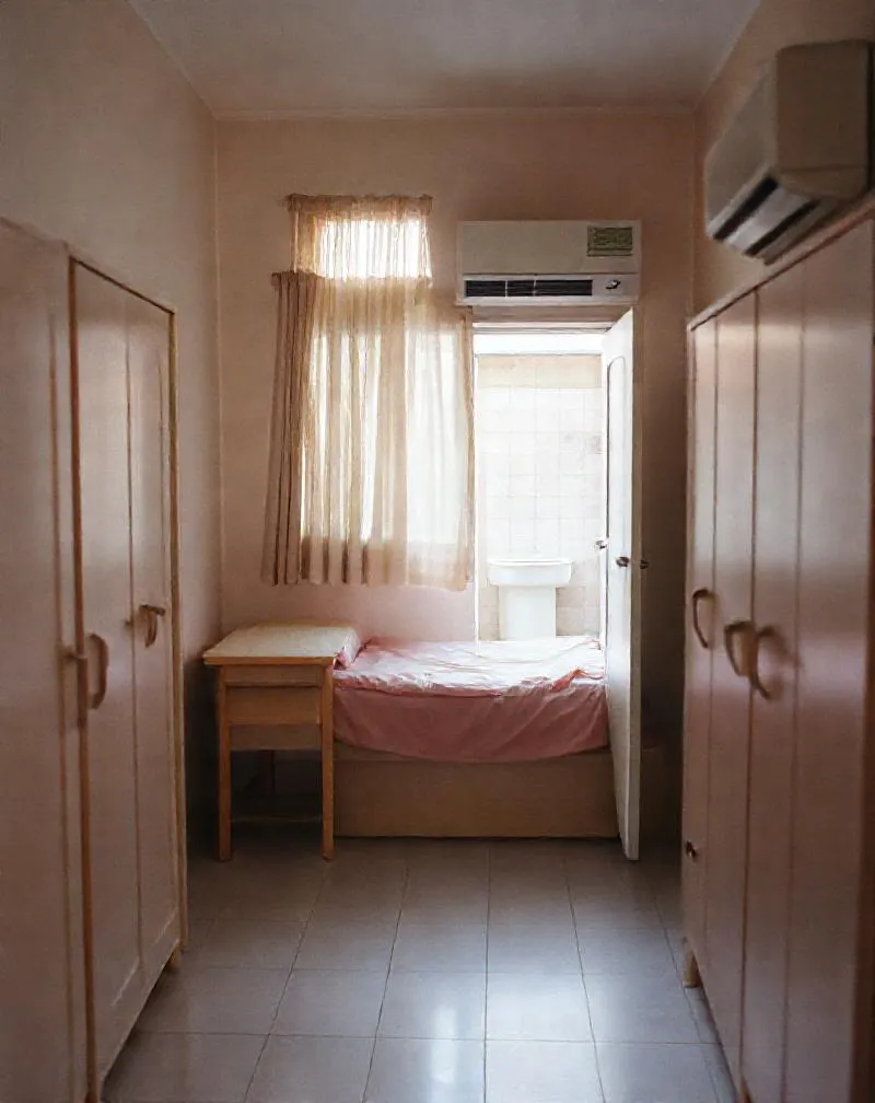 Kamar di Wisma Melati: meja belajar kayu di bawah jendela, kasur, lemari dan AC