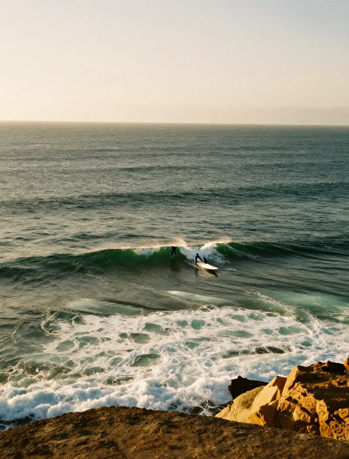 Surfers paddling out at the rocky point break of Ribeira d'Ilhas
