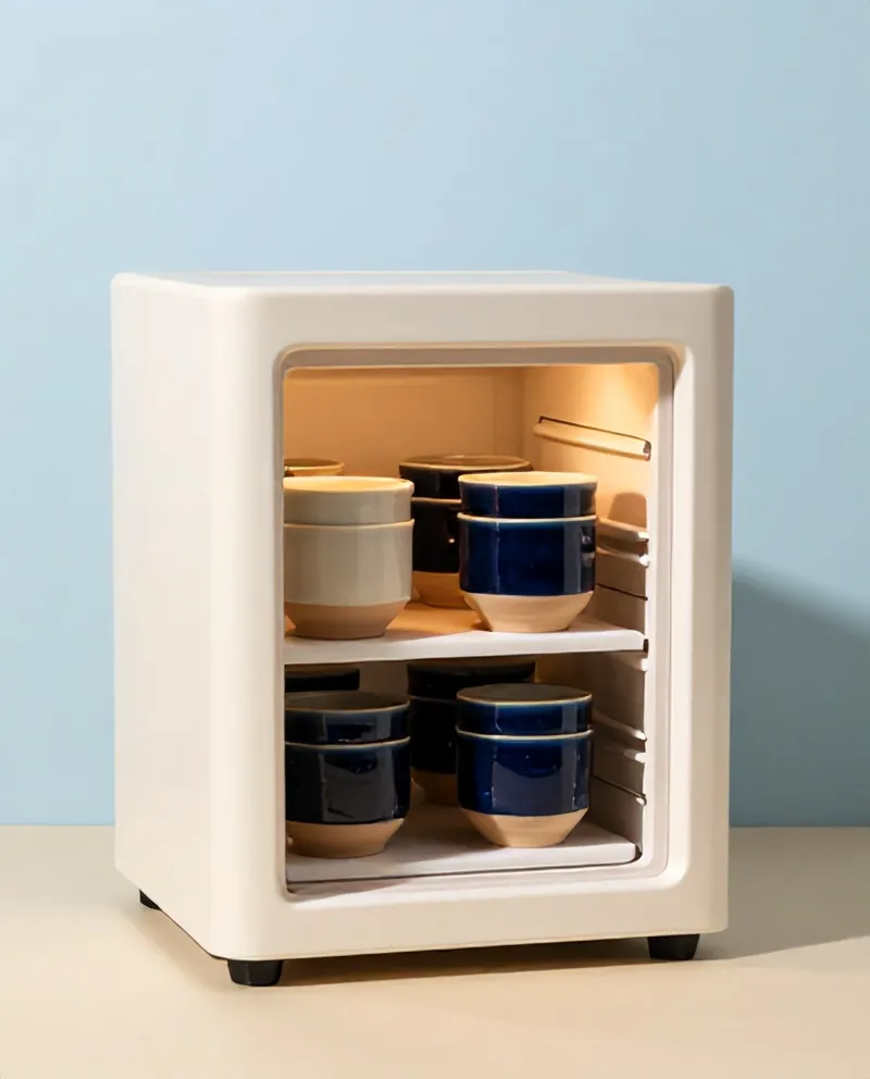 An open electric kiln with glazed cups on its shelves