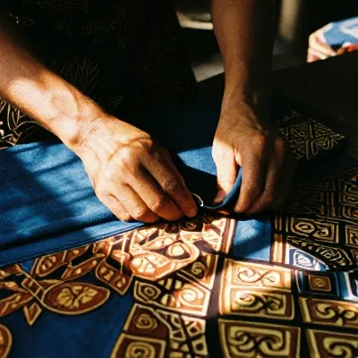 Tangan pembatik melipat kain indigo