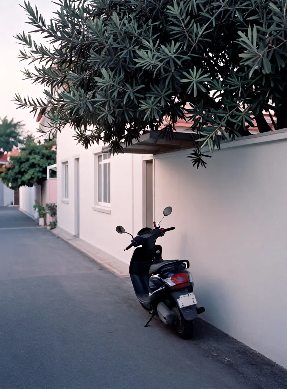 Motor terparkir di carport samping rumah putih