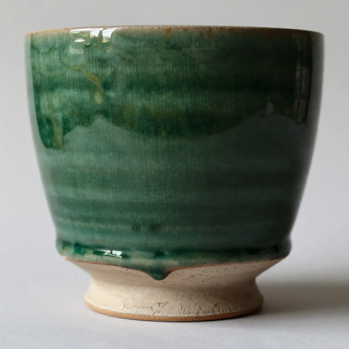 Close-up of glaze pooling and dripping above the kiln-marked foot of a Kiln cup