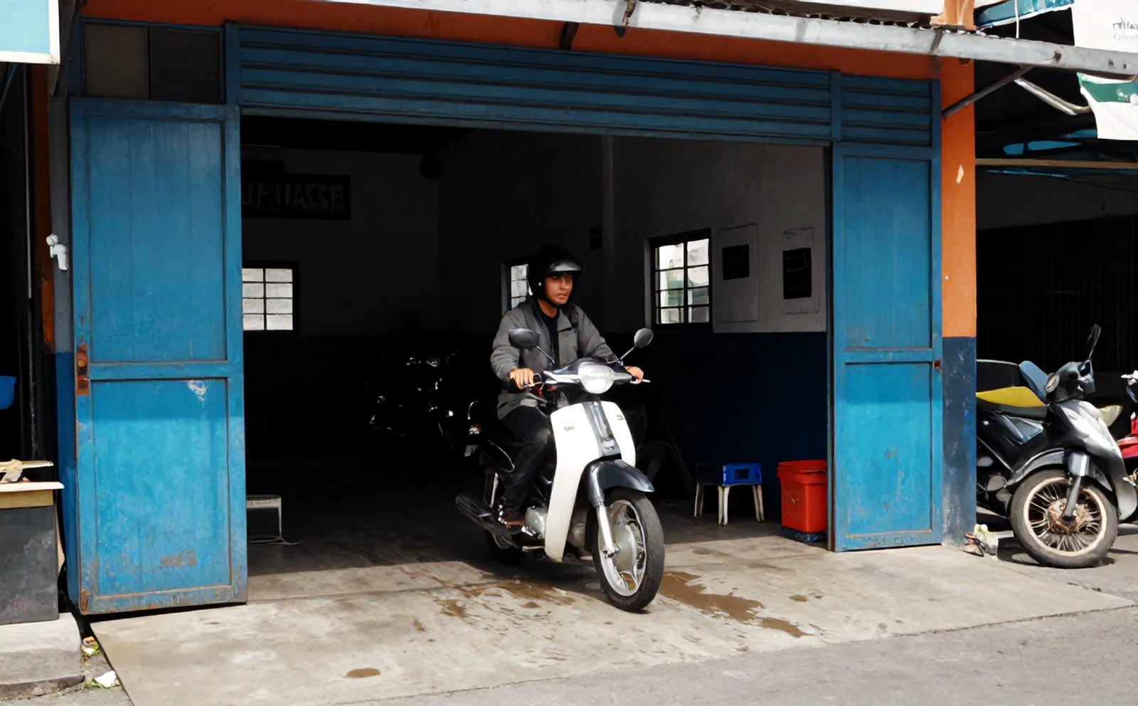Pengendara memarkir motor di depan bengkel