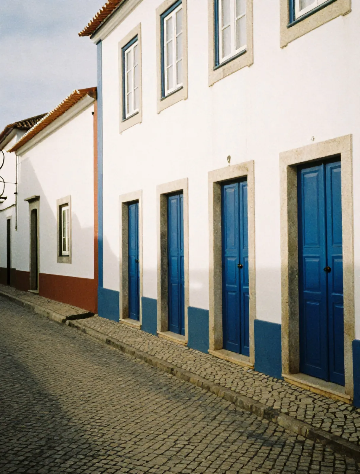 A cobbled lane in Ericeira with blue-trimmed doors
