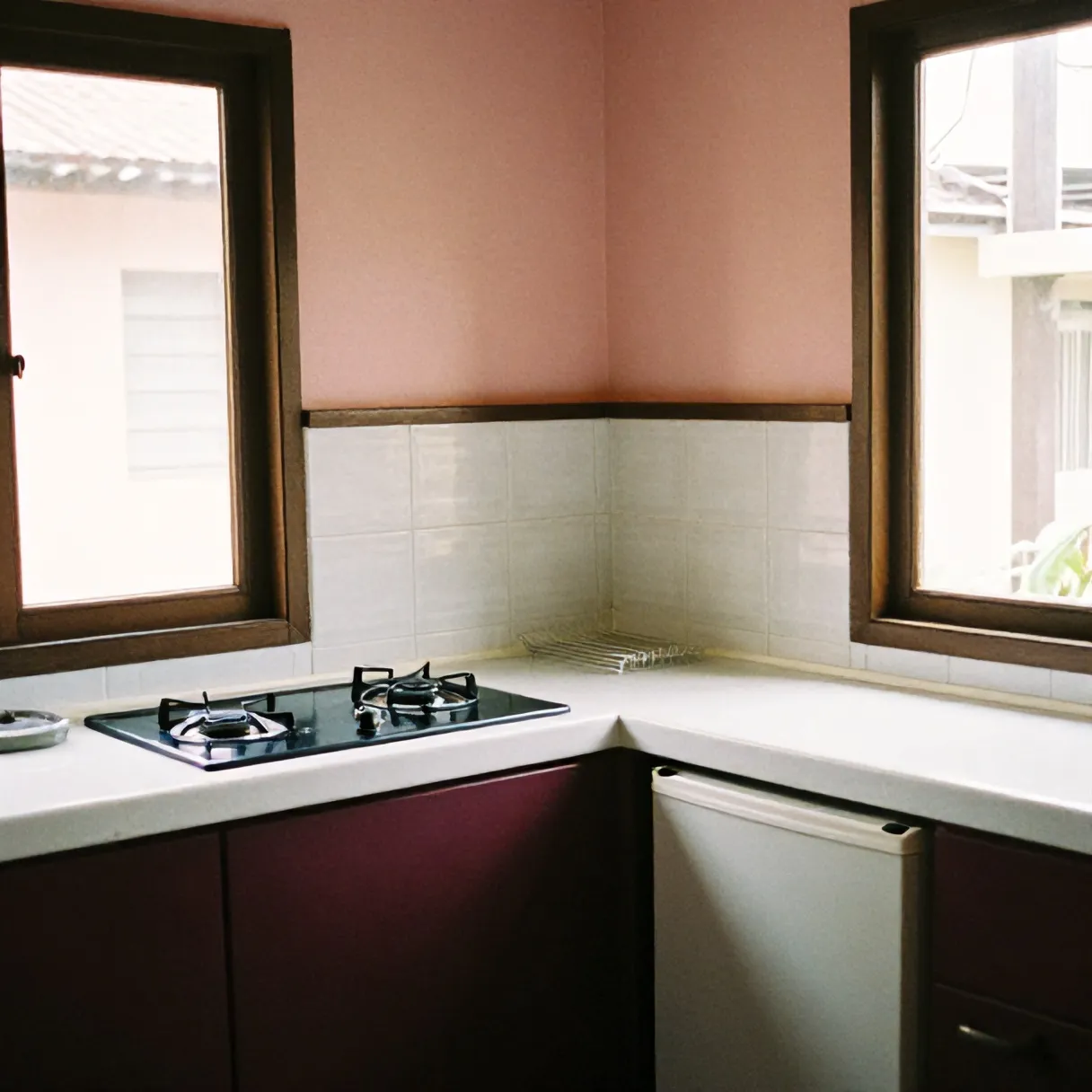Dapur bersama dengan kompor dua tungku, rak piring, dan kulkas kecil