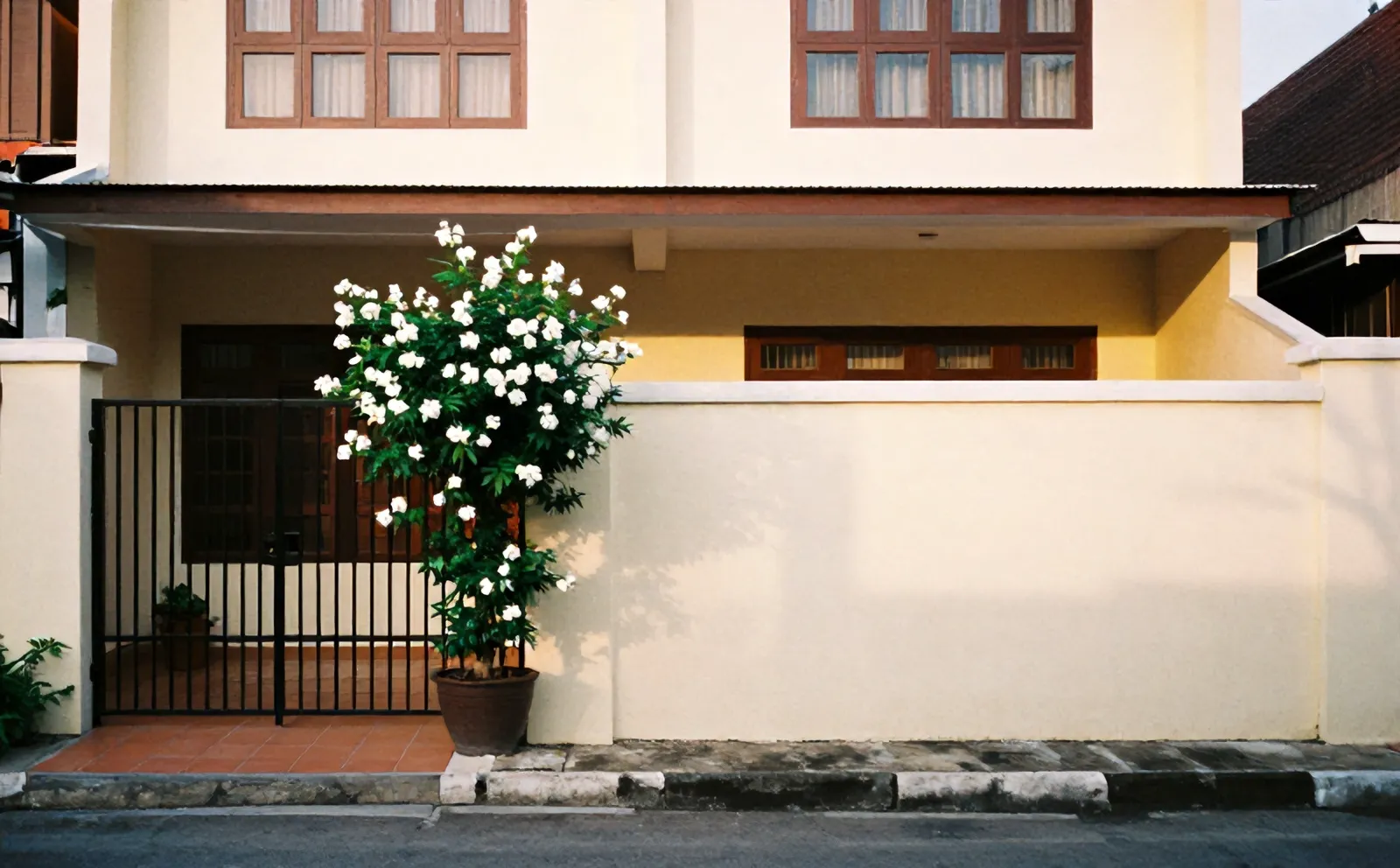 Rumah dua lantai Wisma Melati di Pondok Cina dengan pagar besi dan pot melati di samping gerbang