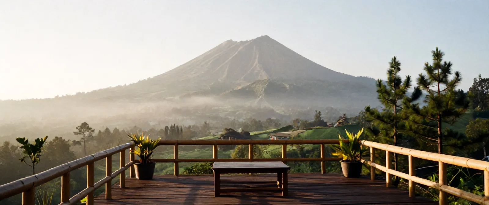 Pemandangan dari teras kayu Kopi Lereng ke puncak Merapi di pagi cerah, kabut di lembah