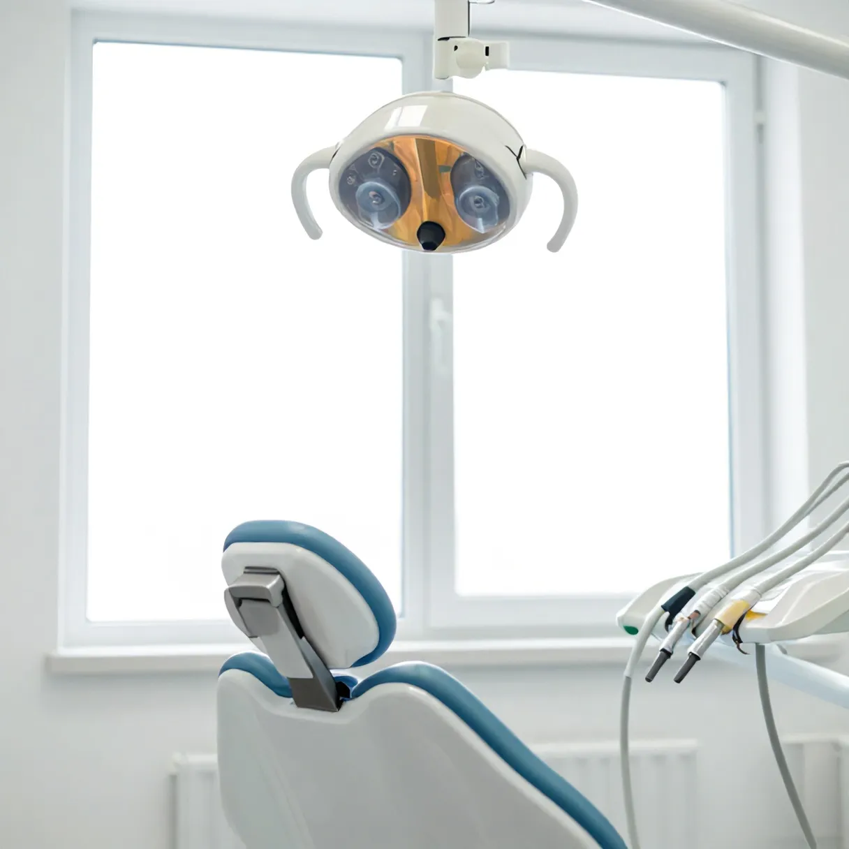 Tangan dokter mengatur lampu periksa di atas kursi dental kosong