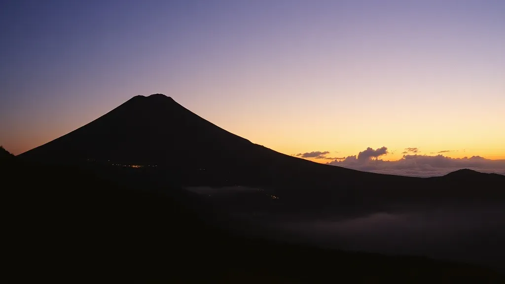 Siluet Merapi saat senja dengan lampu rumah di lereng