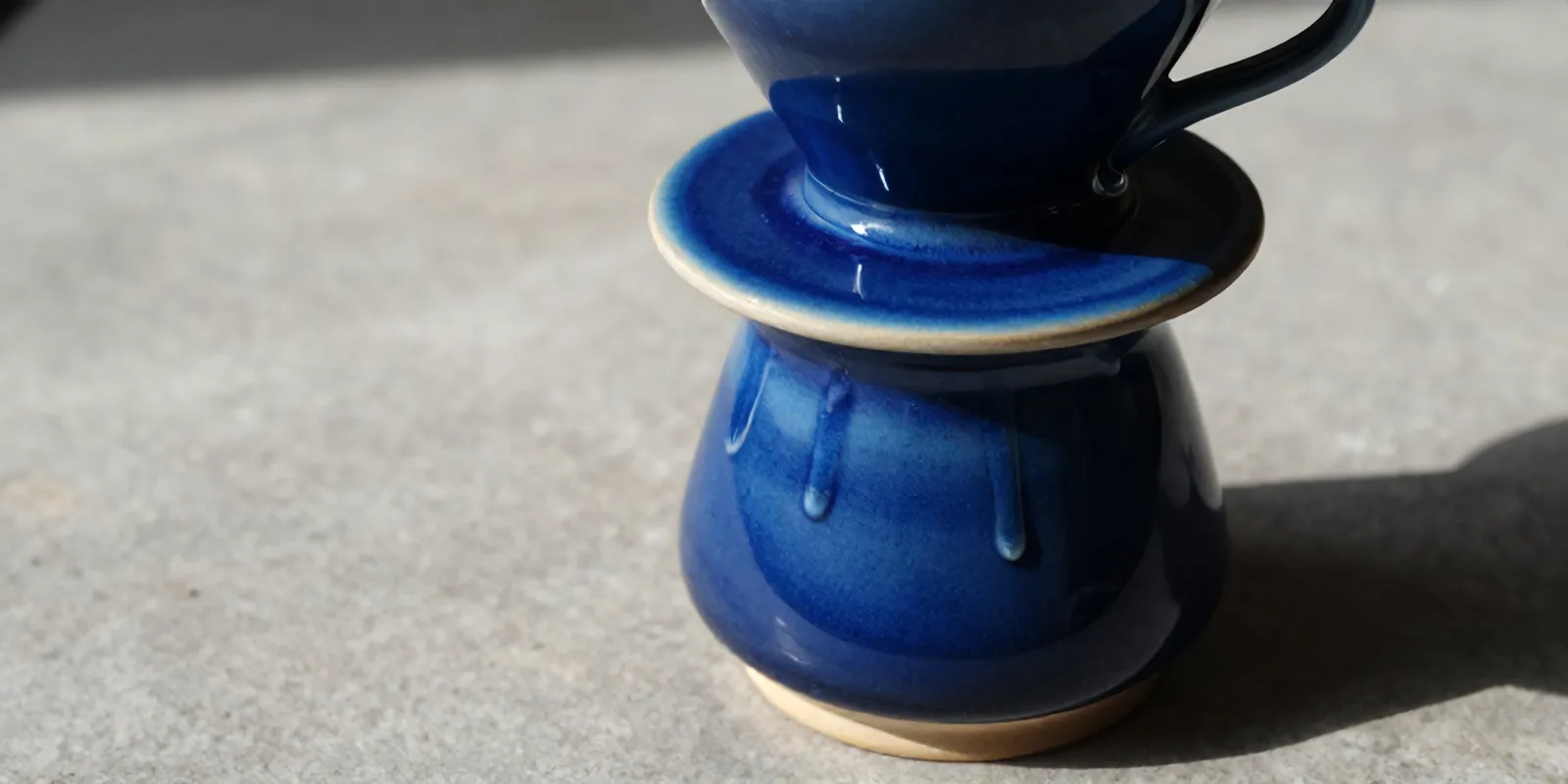 Kiln dripper on its carafe, cobalt glaze running down the side in thick drips to the bare clay foot