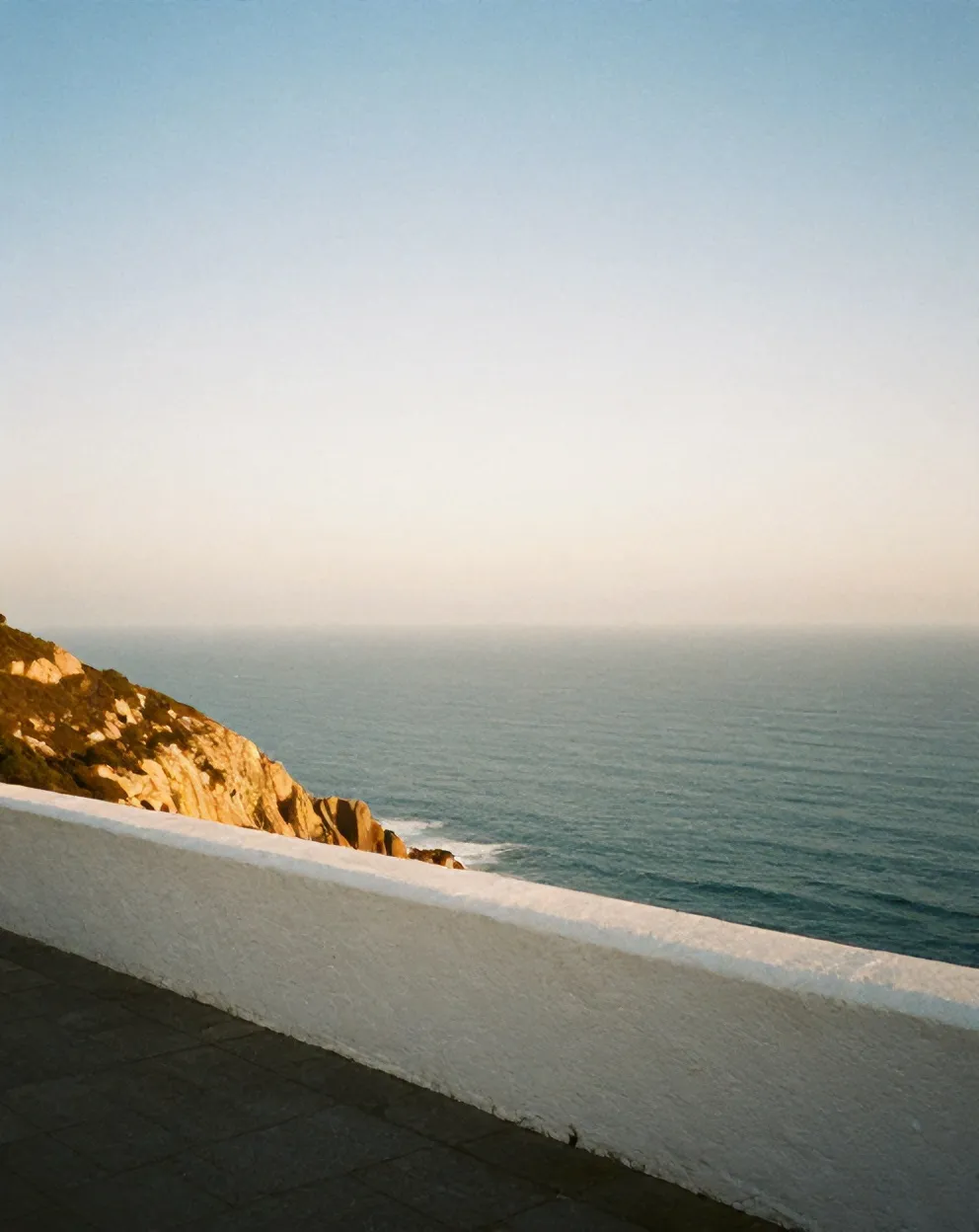 The Atlantic at golden hour, seen over the whitewashed parapet of the terrace at Casa Mirante