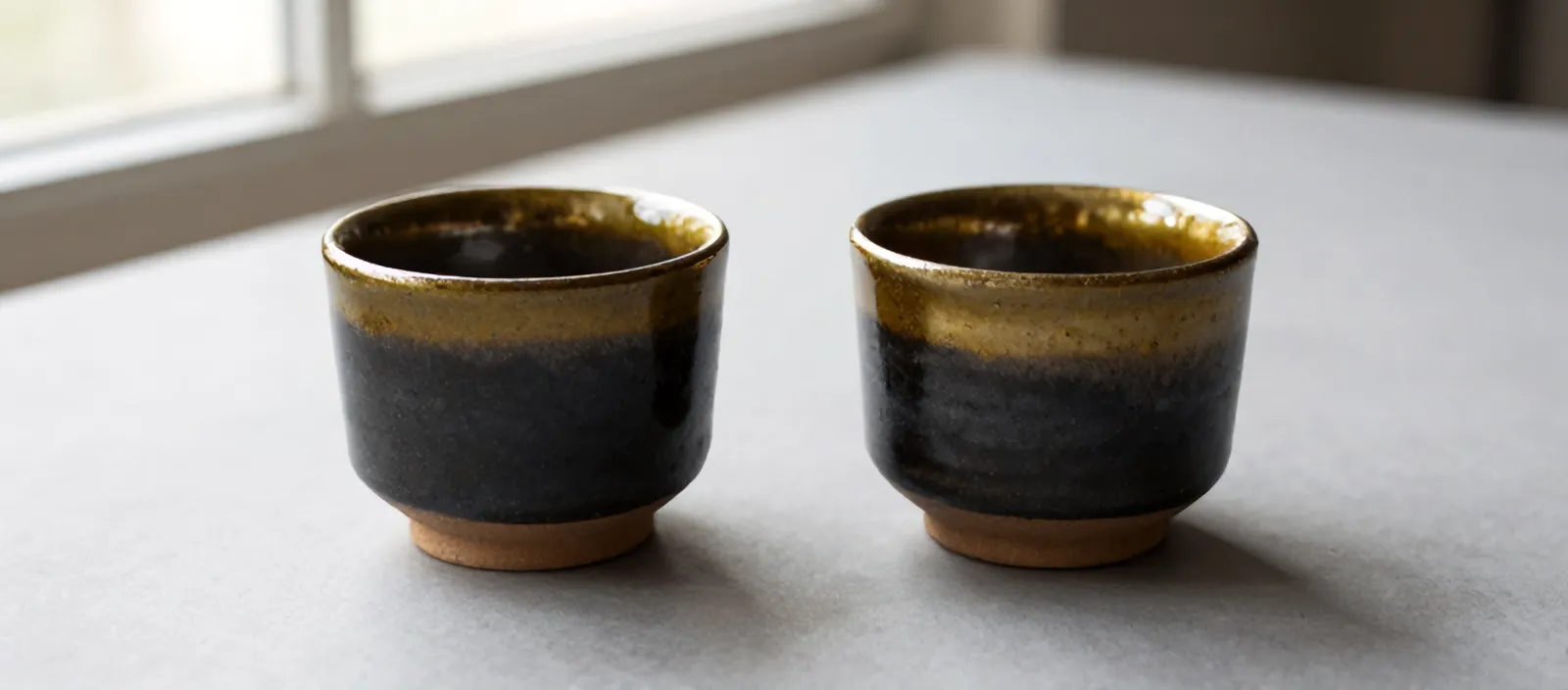 Two handleless Kiln cups side by side, raw clay feet showing