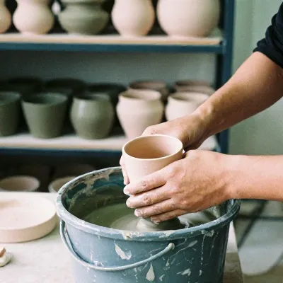 A potter dipping a bisque cup into a bucket of glaze