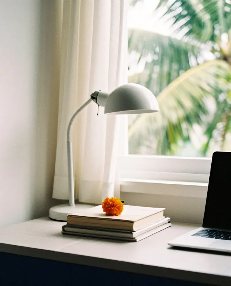 Meja belajar dengan lampu, buku, dan laptop di dekat jendela