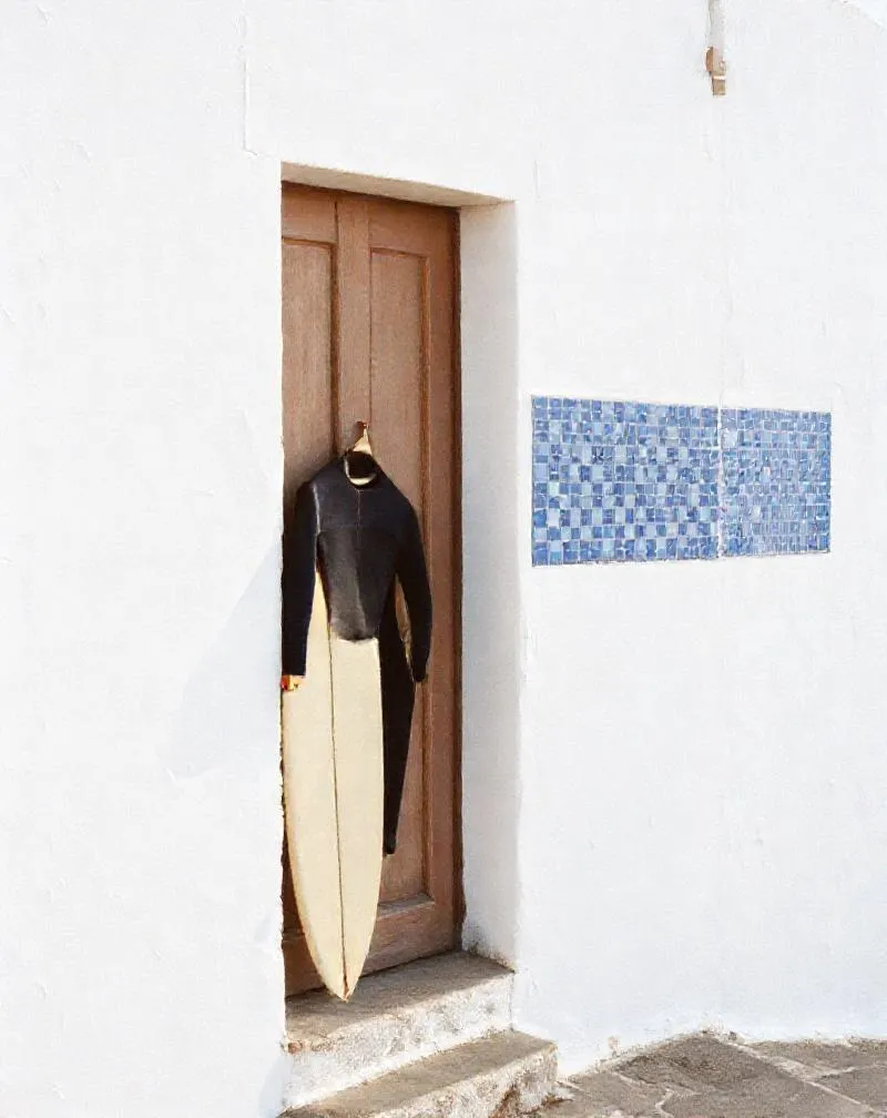 Azulejo tiles on a whitewashed wall with a wetsuit drying beside the door