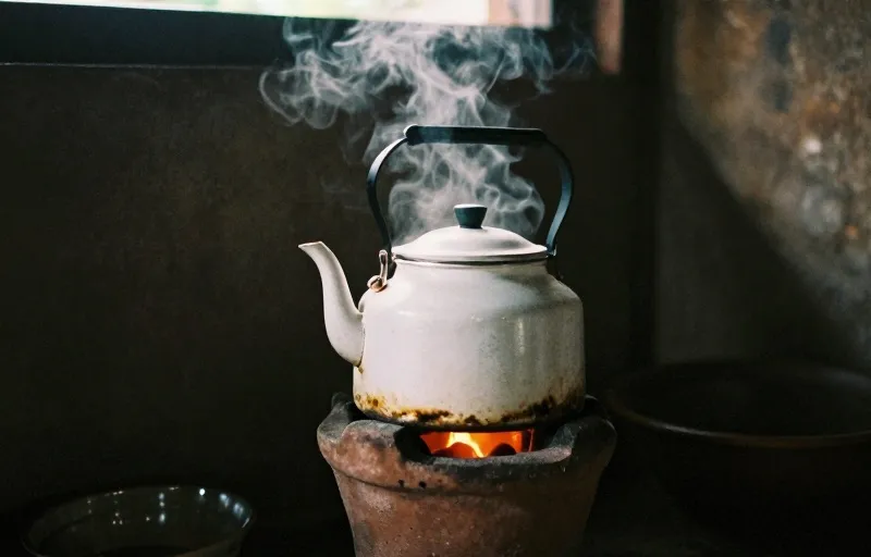 Ceret enamel di atas anglo arang, air dijerang untuk kopi tubruk