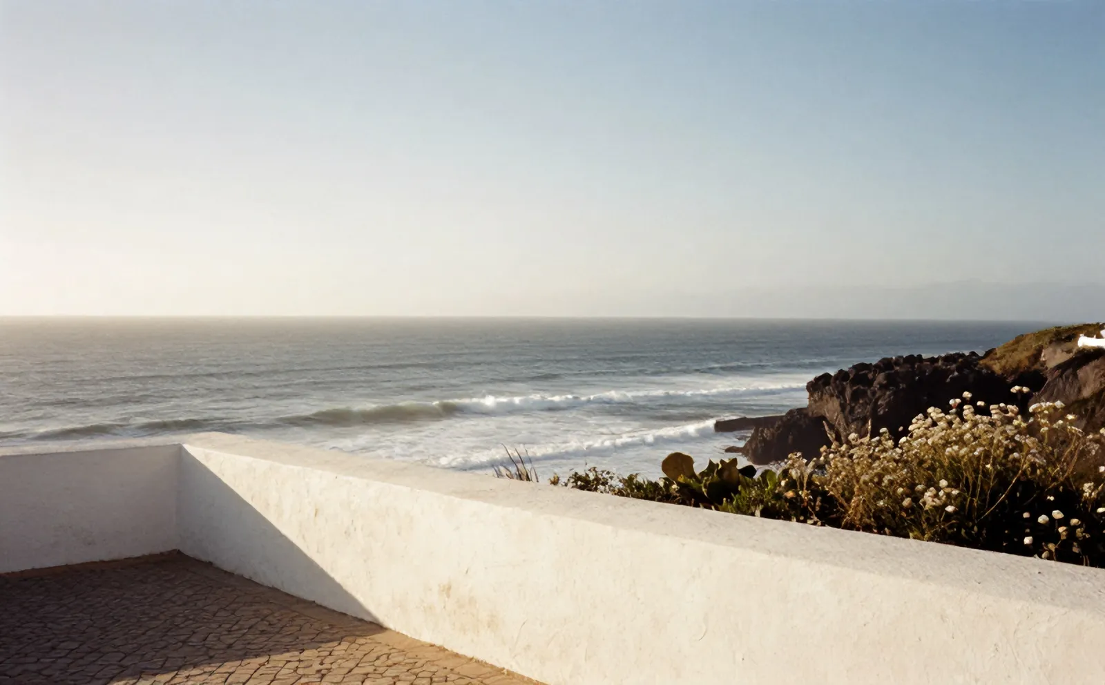 The Atlantic from the whitewashed terrace wall of Casa Mirante, swell lines rolling in below the cliff at Ericeira