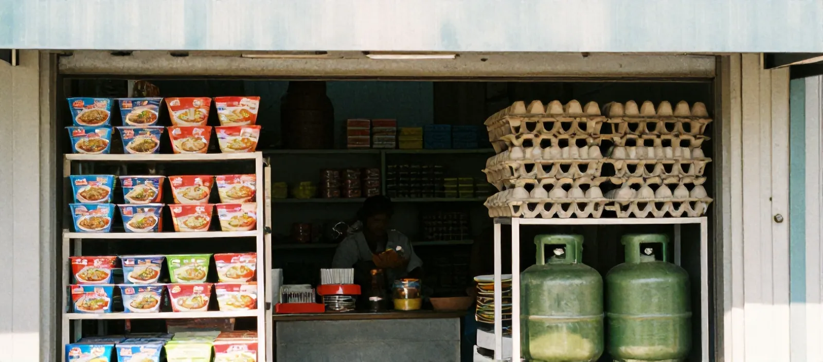 Bagian dalam toko kelontong dengan rak mi instan, telur, dan gas melon