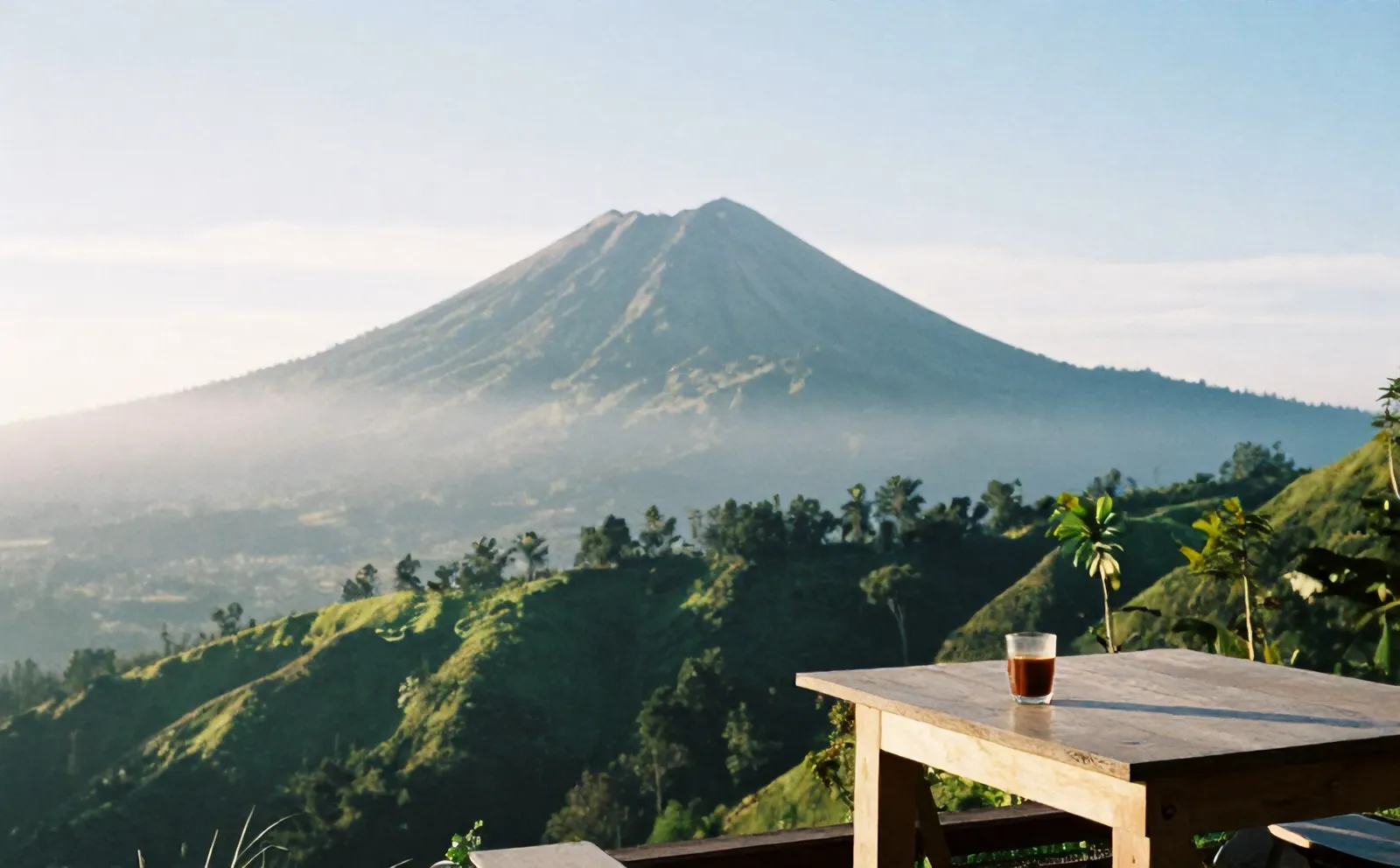 Merapi terlihat jelas di pagi cerah, segelas kopi tubruk di meja teras