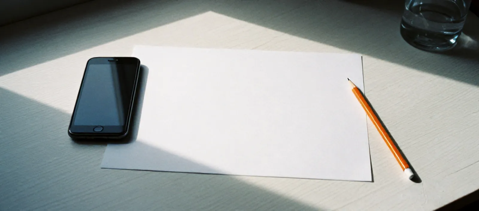 Paper wireframes and a face-down phone on a birch desk