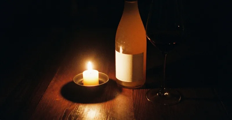 Two tumblers of cloudy orange natural wine by candlelight