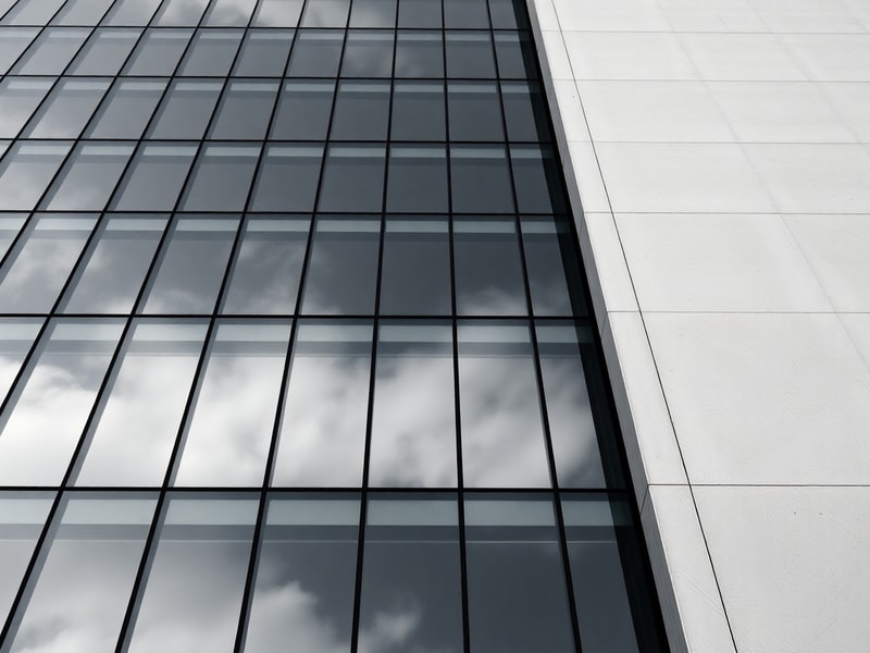 Exterior glass curtain wall reflecting sky in a crisp geometric grid